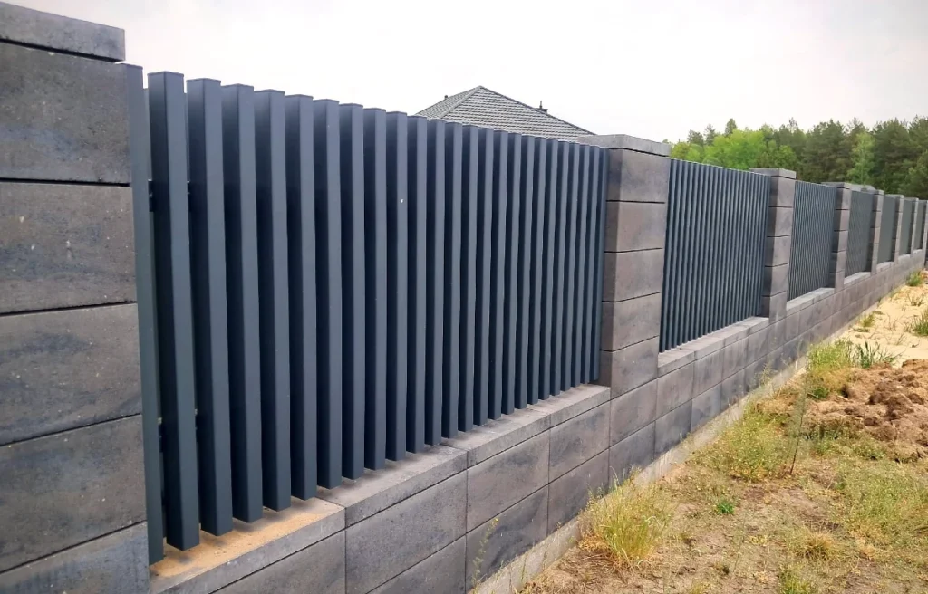 Ogrodzenie murowane z przęsłami: słupy z pustaków ogrodzeniowych i metalowe wypełnienie wykonane na wymiar