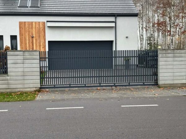 Brama przesuwna Linea antracytowa RAL 7016 między słupkami z bloczków betonowych, realizacja SILD